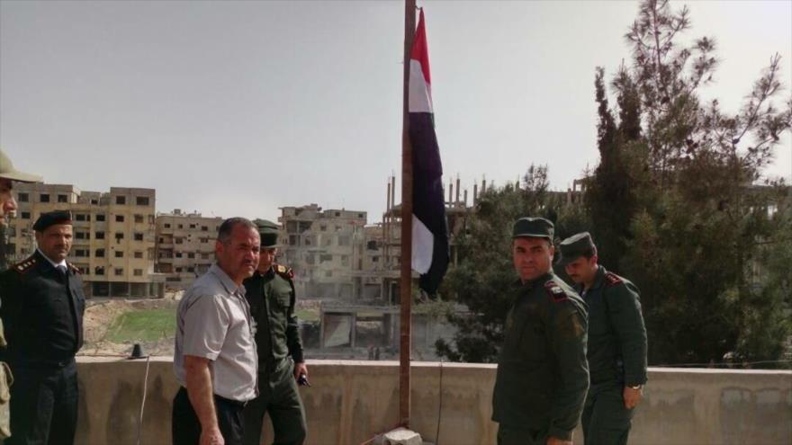 Fuerzas sirias izan la bandera del país árabe en una zona liberada en la región de Guta Oriental, 23 de marzo de 2018.