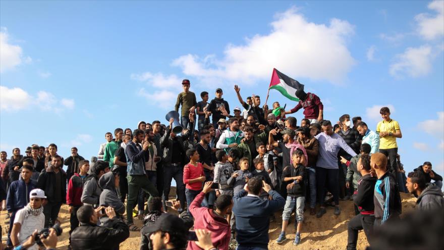 Manifestantes palestinos ondean su bandera nacional durante las protestas del Día de la Tierra en el este de la Franja de Gaza, 30 de marzo de 2018.