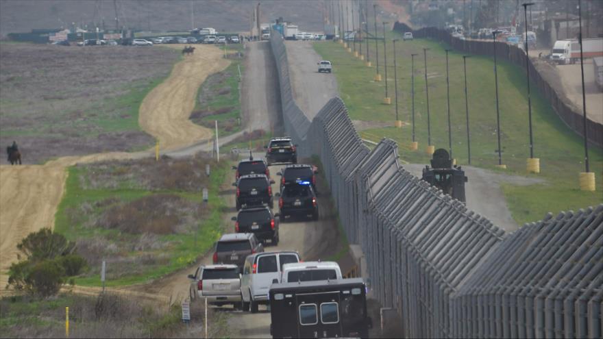 La caravana que transporta al presidente estadounidense, Donald Trump, pasa por una valla fronteriza entre EE. UU. y México, 13 de marzo de 2018.