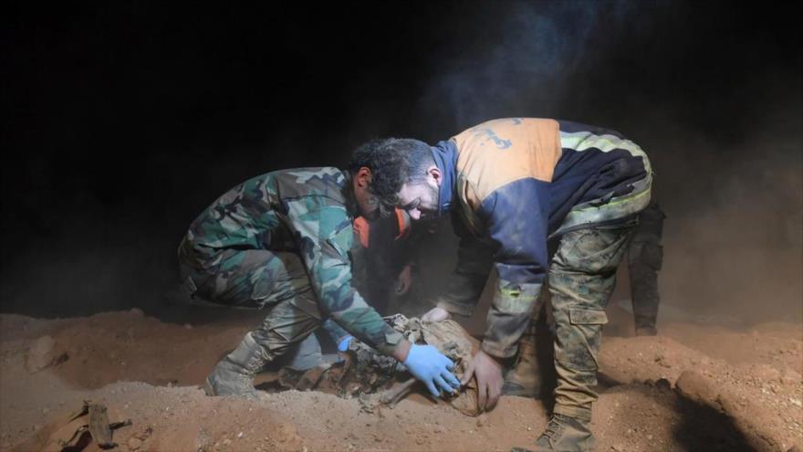 Militares sirios retiran restos humanos de dos fosas comunes encontradas cerca de Al-Raqa, en el norte de Siria, 30 de diciembre de 2017.