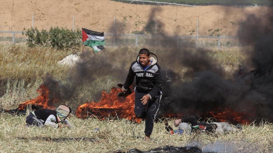 Un palestino busca refugio durante enfrentamientos con fuerzas israelíes luego de la Marcha del Retorno en la Franja de Gaza, 31 de marzo de 2018.