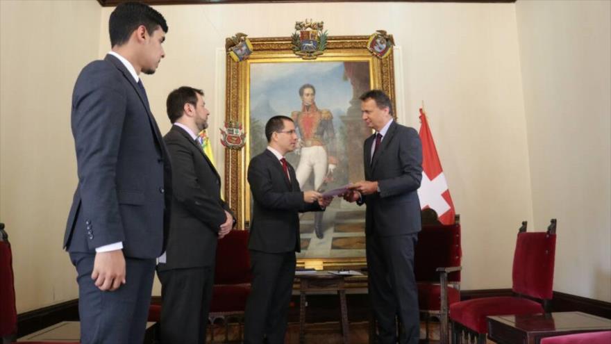 El representante de Suiza en Caracas, Didier Chassot (dcha.) recibe una nota de manos del canciller venezolano, Jorge Arreaza, 2 de abril de 2018.