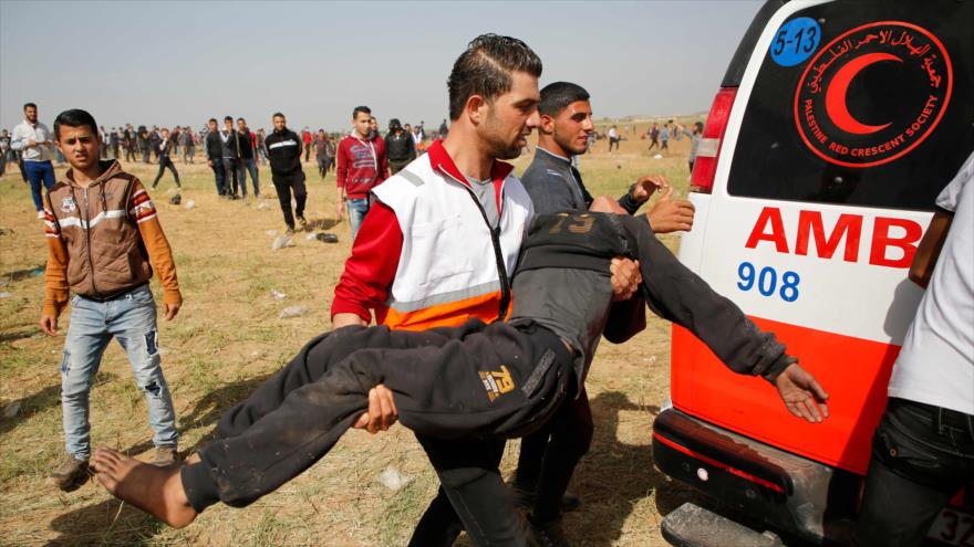 Un médico traslada a un adolescente palestino herido por las fuerzas israelíes en el norte de la Franja de Gaza, 6 de abril de 2018.