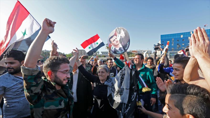 Sirios izan la bandera nacional y portan retratos del presidente Bashar al-Asad en la Plaza Omeya, en Damasco tras ataque de EE.UU., 14 de abril de 2018.