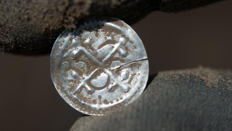 Un arqueólogo muestra una antigua moneda danesa hallada en la isla alemana de Rueguen en el Báltico,13 de abril de 2018.