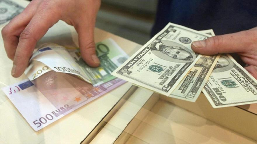 Un hombre cambia billetes de dólar estadounidense (dcha.) con euro.