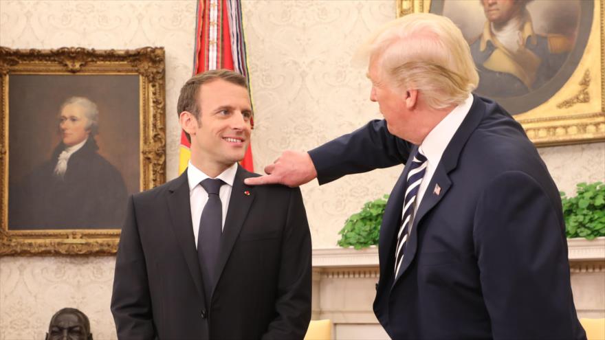 El presidente de EE.UU., Donald Trump (dcha.) quita la caspa de la chaqueta del presidente francés Emmanuel Macron, en Washington, 24 de abril de 2018.
