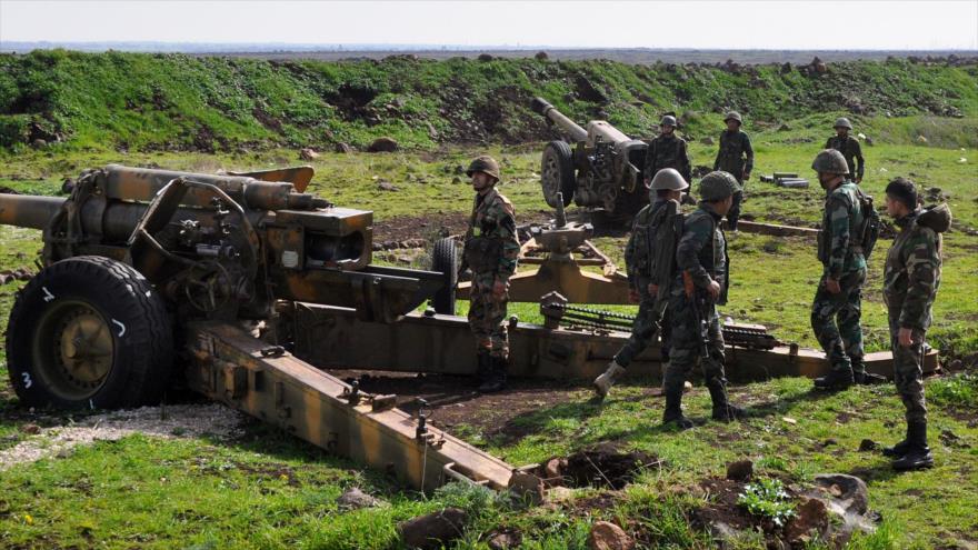 Soldados sirios se paran al lado de un cañón de artillería en el área entre Talbiseh y Al-Rastan en el norte de Homs, 1 de marzo de 2018.