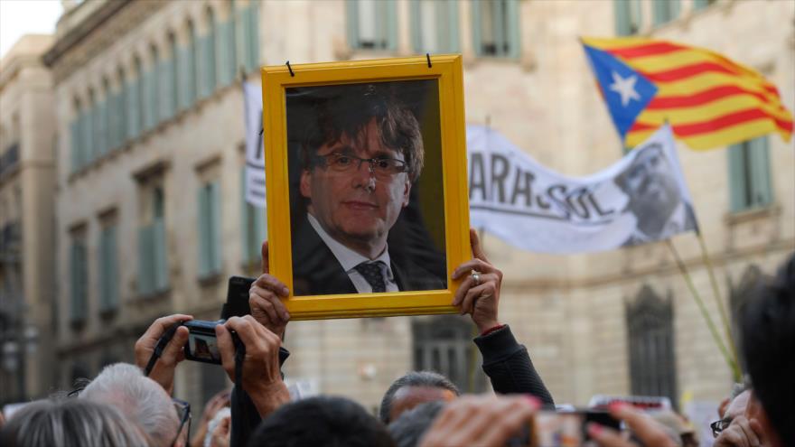 Un manifestante sostiene una foto del ex presidente de Cataluña Carles Puigdemont en una marcha a su favor en Barcelona, 2 de mayo de 2018.