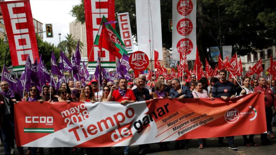 Trabajadores sostienen pancartas y banderas durante un mitin del Primero de Mayo en Málaga (España).