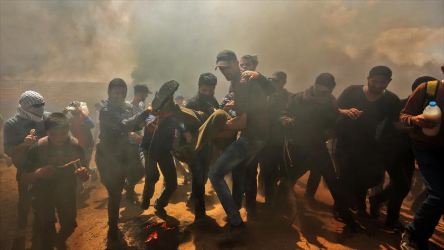 Os palestinos carregam o corpo de um jovem ferido por tiros israelenses na fronteira de Gaza e nos territÃ³rios ocupados, em 14 de maio de 2018.
