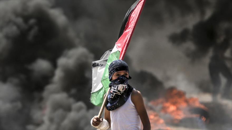 Un menor palestino sostiene la bandera nacional de Palestina en una manifestación en la Franja de Gaza, 14 de mayo de 2018.