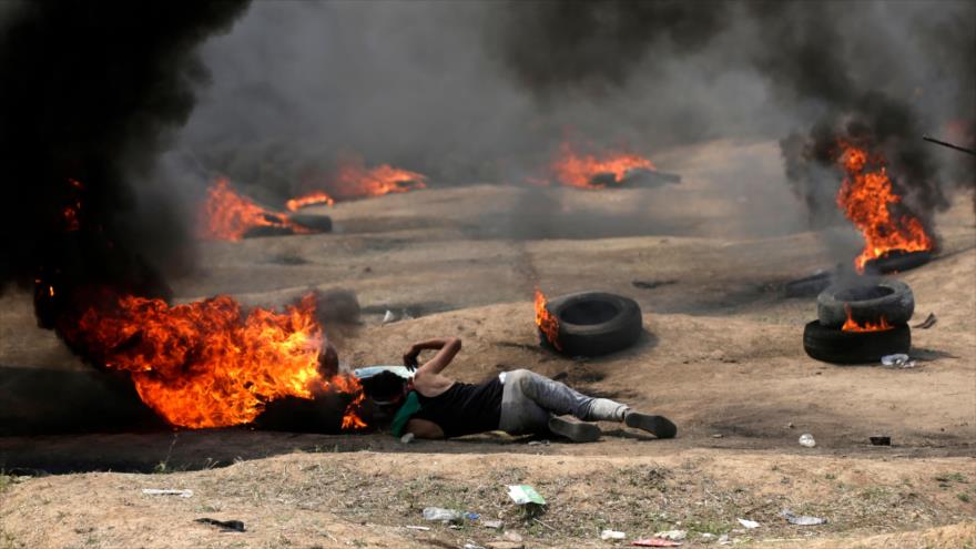 Un manifestante palestino en medio de los neumáticos encendidos contra las fuerzas israelíes, Franja de Gaza, 14 de mayo de 2018.