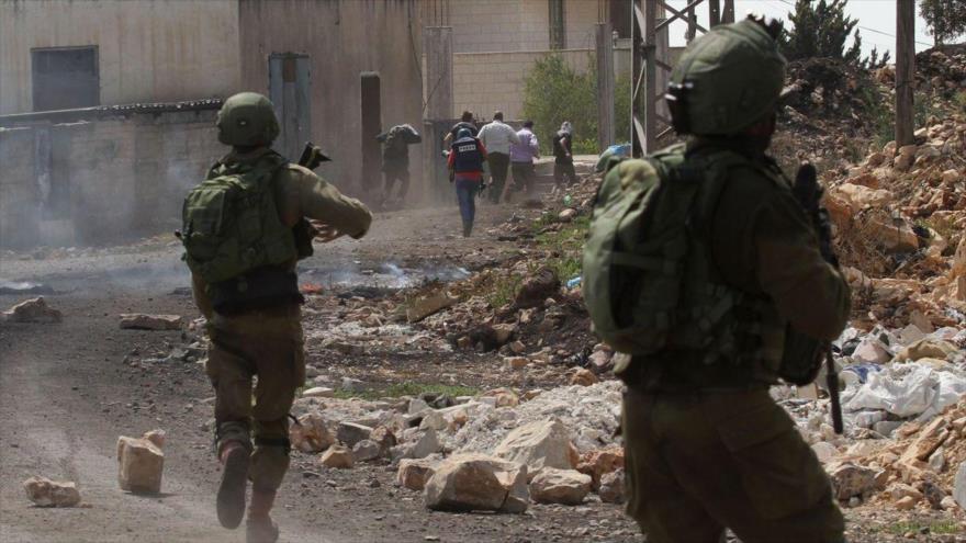 Soldados israelíes apuntan contra palestinos en una localidad cisjordana.