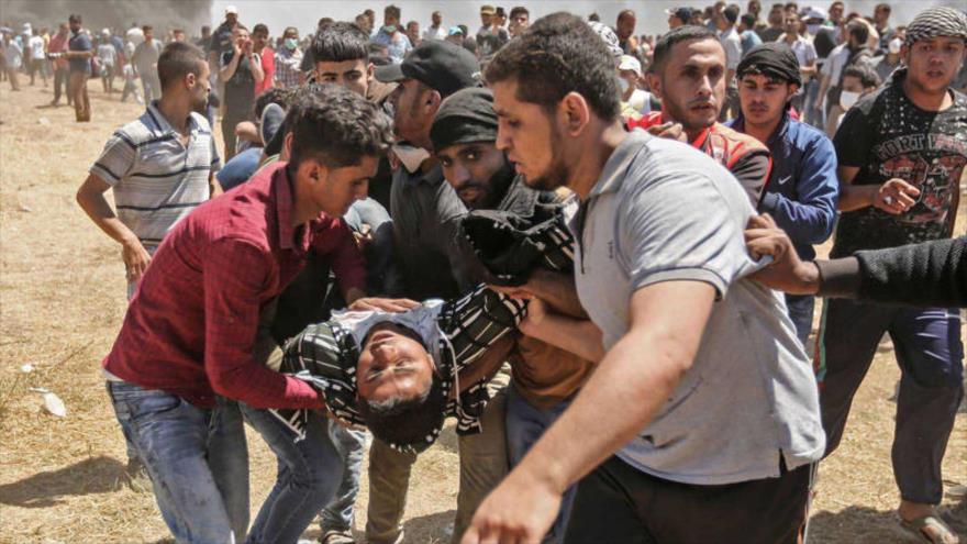 Palestinos llevan a un hombre herido en las protestas en la Franja de Gaza, 14 de mayo de 2018. 