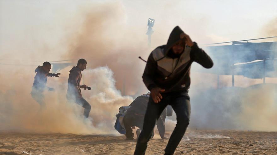 Los manifestantes palestinos huyen de gas lacrimógeno que lanzaron las fuerzas israelíes en el centro de la Franja de Gaza, 15 de mayo de 2018.