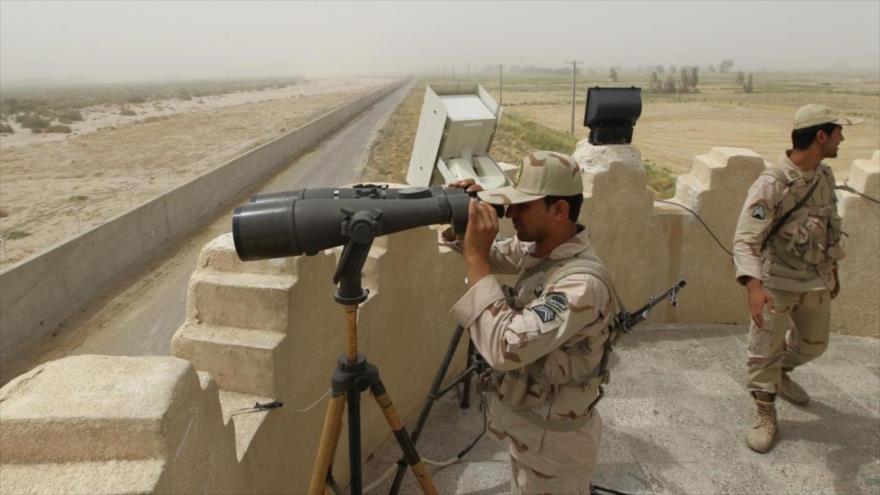 Un guardia fronterizo iraní mira a través de un par de binoculares.