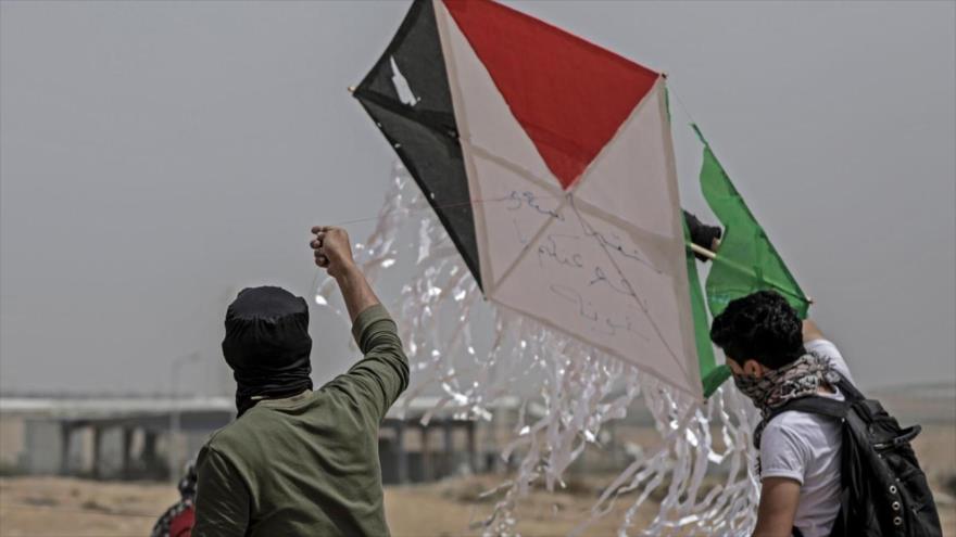 Dos manifestantes palestinos tratan de volar un acometa en señal de rechazo a la ocupación del régimen israelí de los territorios ocupados de Palestina.