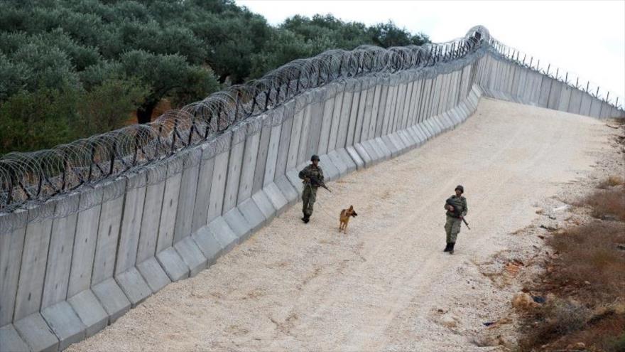 Soldados turcos vigilan cerca del muro instalado entre la frontera de Turquía y Siria.