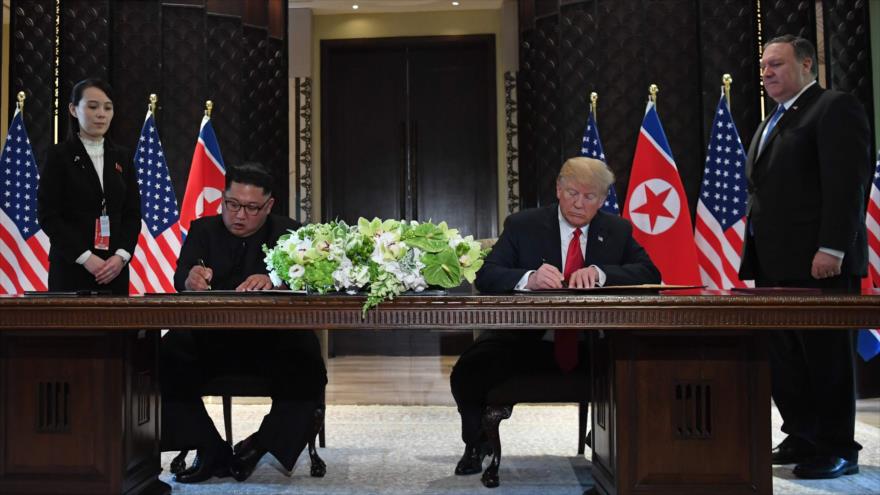 El presidente de EE.UU., Donald Trump (dcha.), y el líder norcoreano, Kim Jong-un (izda.), firman documentos, 12 de junio de 2018.