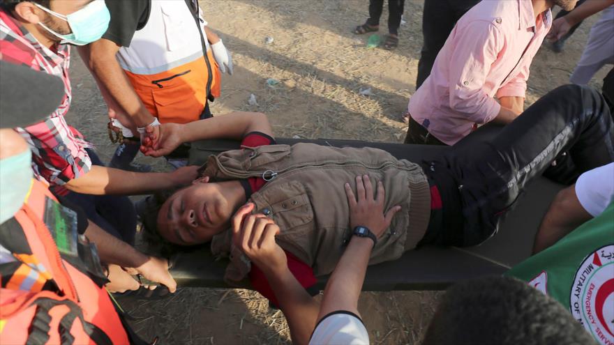 Palestinos trasladan a un manifestante herido por disparos de los soldados israelíes en la Franja de Gaza, 22 de junio de 2018.