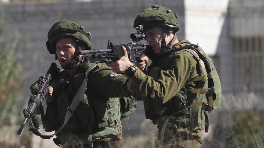 Soldados israelíes apuntan con sus rifles automáticos.