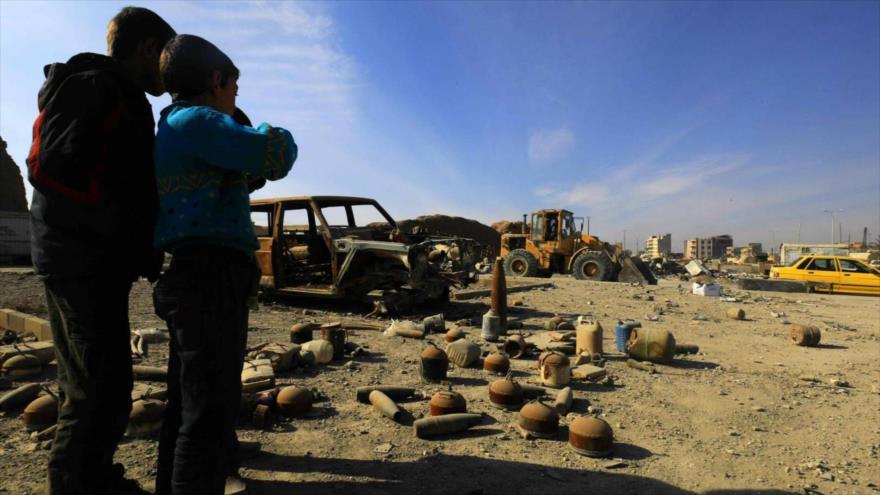 Niños sirios observan proyectiles y minas sin detonar que fueron colocados por terroristas y que yacen en una calle en Al-Raqa, 16 de enero de 2018.