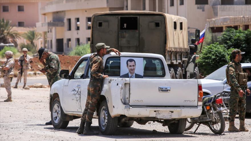 Soldados sirios en un vehículo con la foto del presidente Bashar al-Asad y policías militares rusos en el paso de Nasib en Daraa, 7 de julio de 2018.