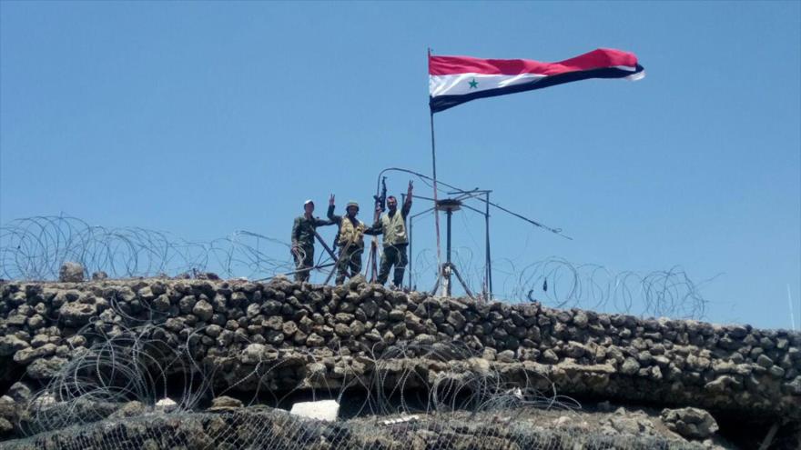 Soldados del Ejército sirio enarbolan su bandera nacional en la cima de una colina conocida como Tallet Al-Hara en Daraa, 17 de julio de 2018.