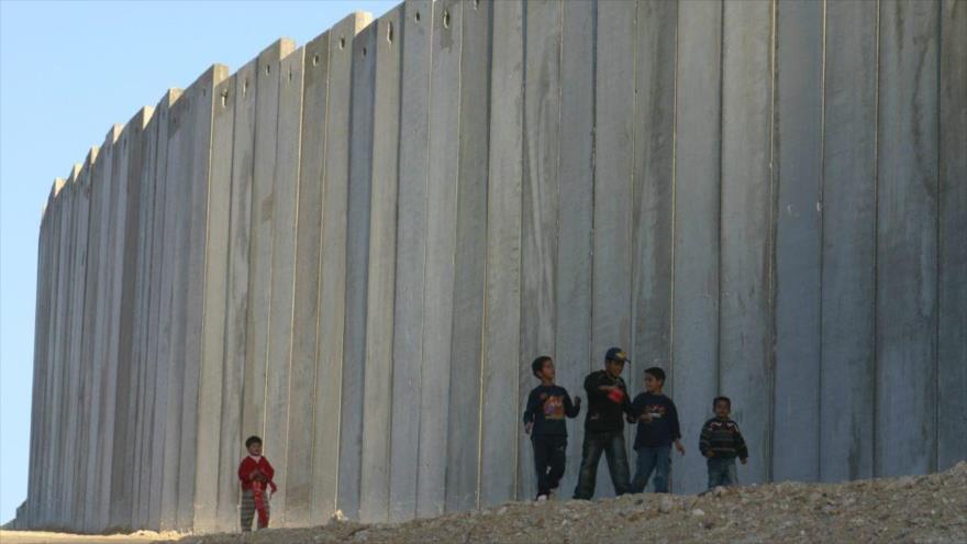 Niños palestinos a lo largo de la barrera de separación israelí en la ocupada ciudad palestina de Cisjordania.