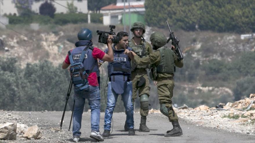 Un soldado israelí se enfrentan a un periodista palestino en la aldea de Kfar Qaddum, cerca de Nablus, en la ocupada Cisjordania, 11 de mayo de 2018. 