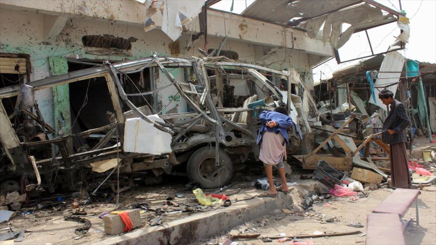 Varios yemeníes observan los restos del autobús destruido por el ataque aéreo de la coalición encabezada por Arabia Saudí en Saada. (Fuente: AFP)
