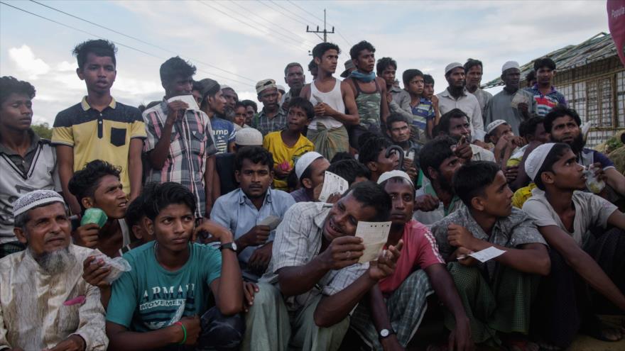 Refugiados rohingyas hacen cola en un centro de distribución de ayuda en un campo de refugiados en Bangladés, 12 de agosto de 2018. Foto: AFP 