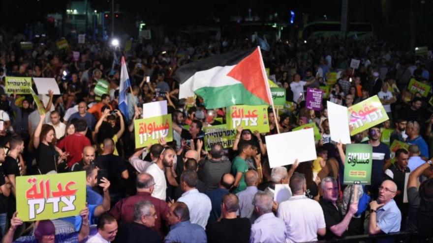 Israelíes ondean la bandera palestina en una protesta en Tel Aviv contra la ley de estado-nación judío, 11 de agosto de 2018.