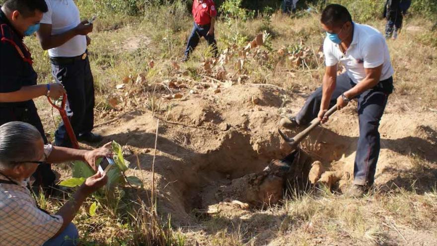 Un operario desenterrando un cadáver en una fosa clandestina en algún paraje de México.