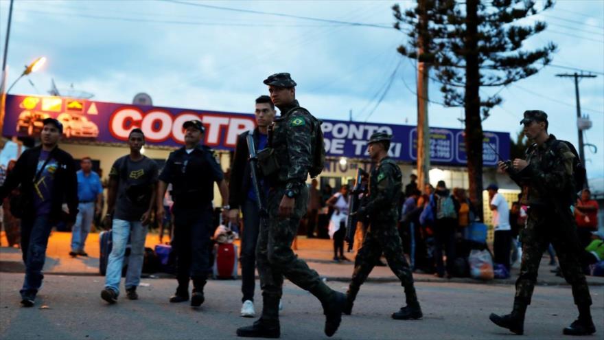 Soldados del Ejército brasileño patrullan en una calle junto a los migrantes venezolanos, estado de Roraima, Brasil, 19 de agosto de 2018.