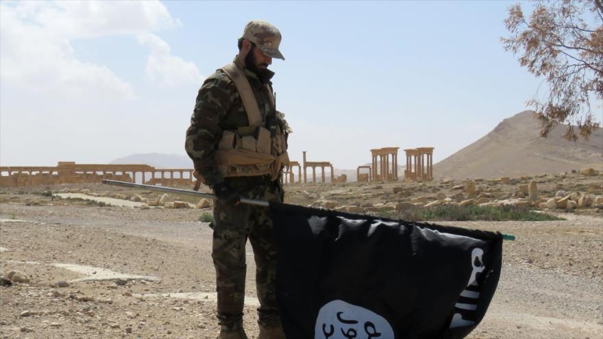 Soldado sirio sostiene una bandera del grupo terrorista Daesh cerca de la parte histórica de Palmira, 27 de marzo de 2016. (Foto: AFP)