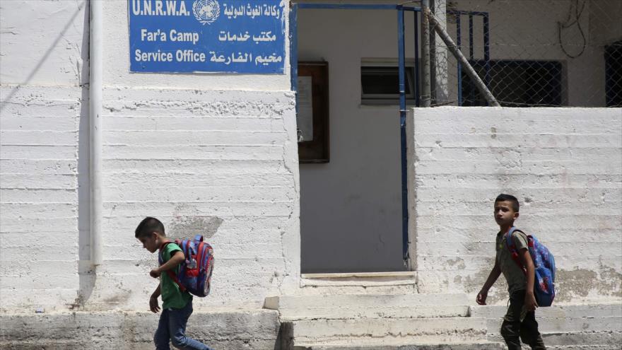 Escolares palestinos pasan por la oficina de servicio de la UNRWA en un campo de refugiados cerca de Cisjordania, 3 de septiembre de 2018. (Foto: AFP)