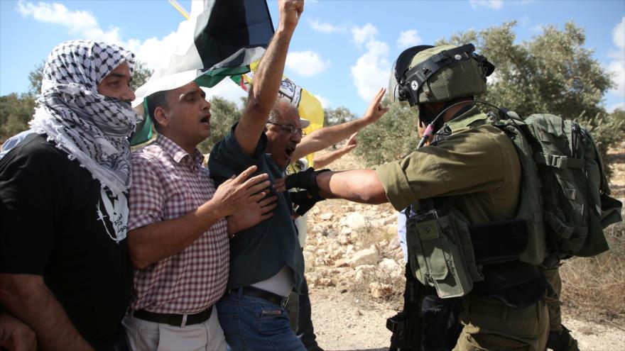 Un soldado israelí trata de impedir una manifestación de palestinos contra la confiscación de las tierras ocupadas, Nablus, 28 de julio de 2018. (Foto: AFP)