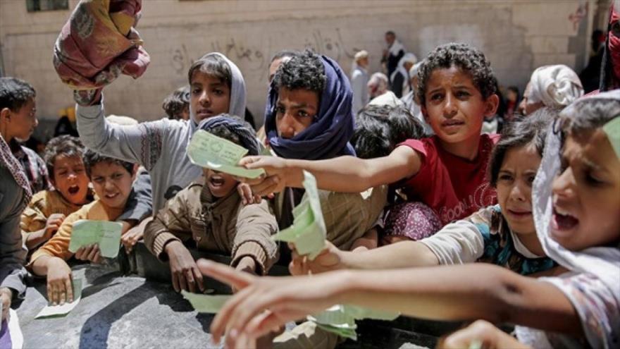 Niños yemeníes presentan documento para recibir comida de una organización caritativa local.