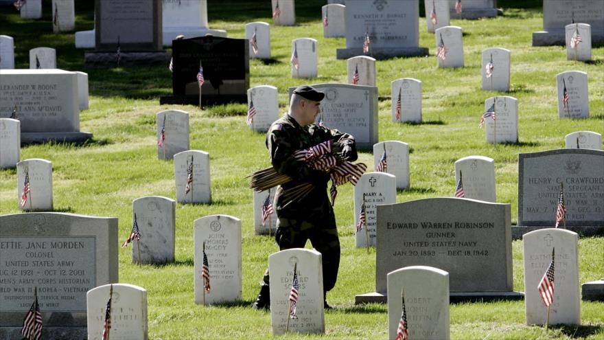 Un militar del Ejército de EE.UU. coloca banderas en tumbas de veteranos en el Cementerio Nacional de Arlington, Virginia, mayo de 2005. (Foto: AFP)