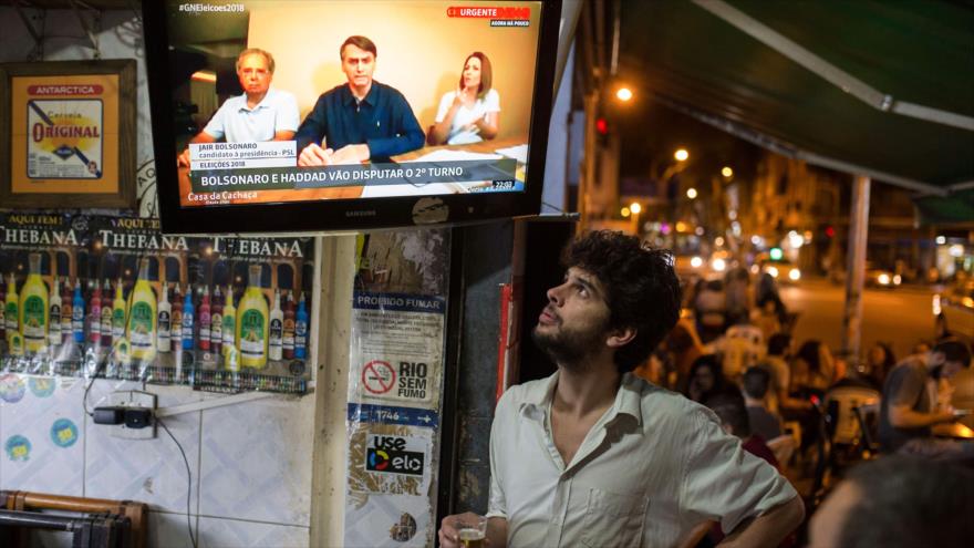 La gente escucha las declaraciones del candidato presidencial Jair Bolsonaro en un bar en Río de Janeiro, Brasil, 7 de octubre de 2018. (Foto AFP)