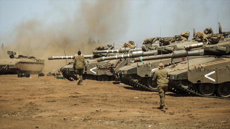Soldados israelíes pasan junto a tanques modelo Merkava Mark IV del ejército de Israel en una maniobra militar.