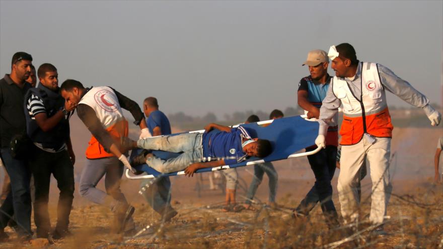 Miembros de la Media Luna Roja llevan a un niño palestino herido durante una manifestación en la Franja de Gaza, 22 de junio de 2018. (Foto: AFP).