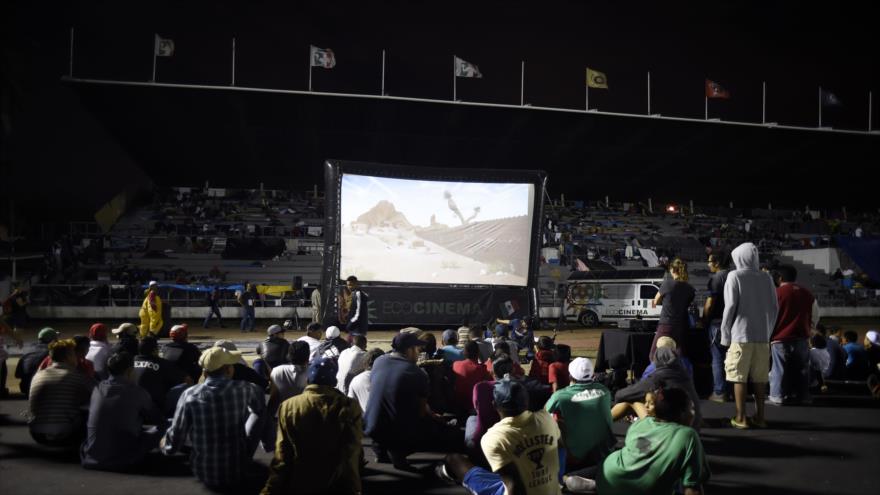 Migrantes centroamericanos ven una película mientras descansan en un refugio establecido en la Ciudad de México, 7 de noviembre de 2018, (Foto: AFP)
