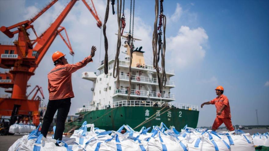 Obreros descargan bolsas de productos químicos en un puerto de Zhangjiagang, en la provincia oriental china de Jiangsu, 7 de agosto de 2018.