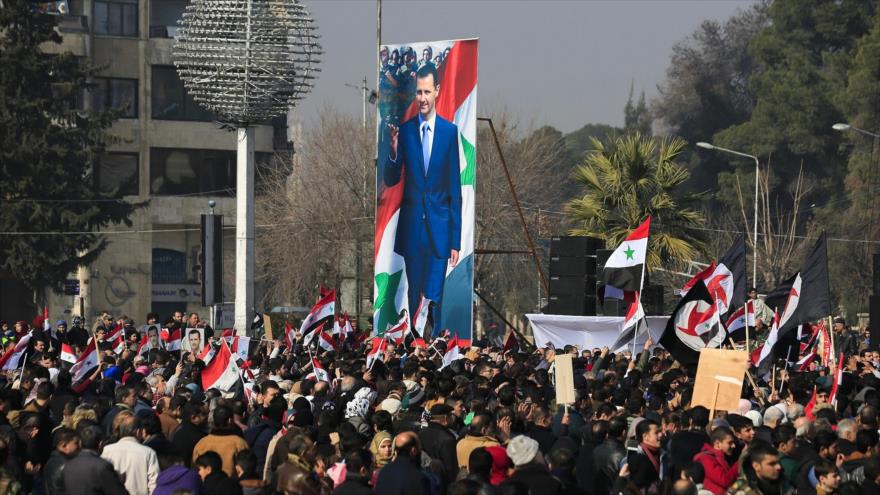 Simpatizantes del Gobierno sirio sostienen la bandera nacional y las imágenes del presidente Bashar al-Asad en Alepo, 19 de enero de 2017. (Foto: AP)