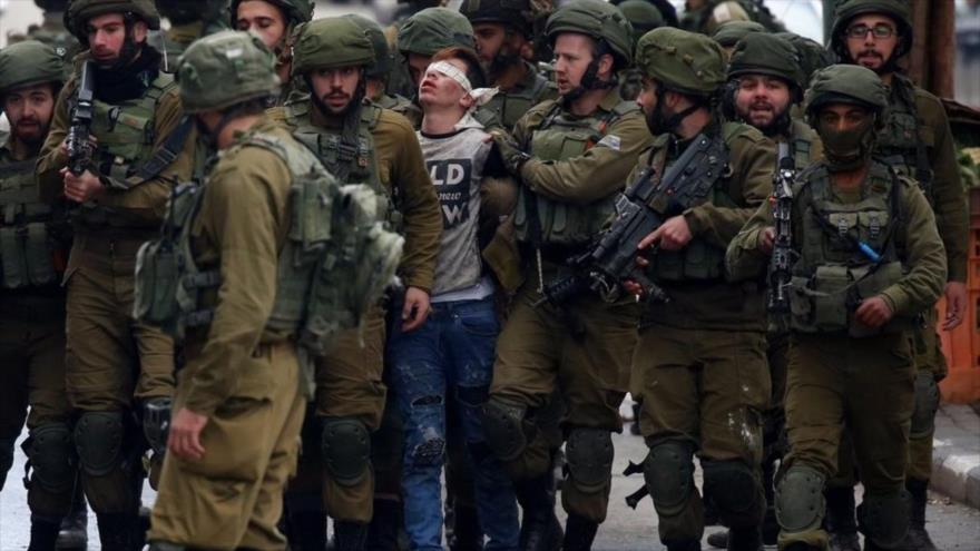 Soldados israelíes detienen a un joven palestino durante unas protestas en la ocupada Cisjordania.