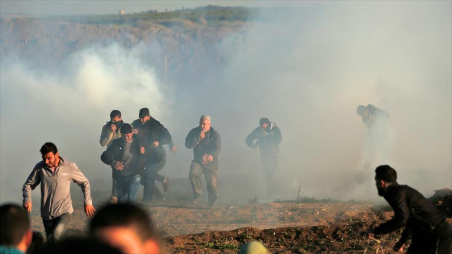 Manifestantes palestinos atraviesan humos de gas lacrimógeno disparados por militares israelíes al este de Gaza, 11 de enero de 2019. (Foto: AFP)