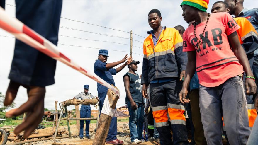 Un policía aleja a los mineros durante una operación de rescate en la mina Cricket en Kadoma, en Zimbabue, 15 de febrero de 2018. (Foto: AFP)